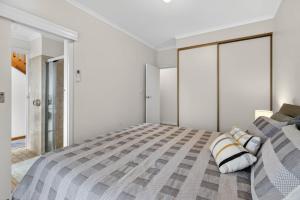 a white bedroom with a large bed with striped pillows at 4 1 Harbour View Terrace BYO Linen in Victor Harbor +38 photos
