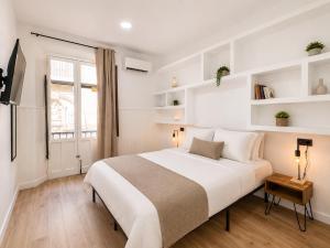 a white bedroom with a large bed and a window at Casa Antares Granada in Granada