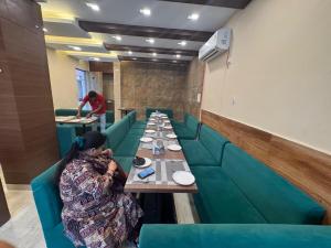 a woman sitting at a long table in a restaurant at Hotel Green Land in Mathura
