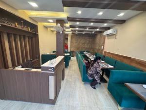 a woman sitting at a counter in a restaurant at Hotel Green Land in Mathura