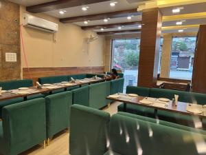 a dining room with green chairs and tables and a person at Hotel Green Land in Mathura +14 photos