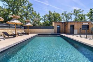 a swimming pool with two umbrellas on a patio at Lodge Spa Celeste in Sarlat-la-Canéda +15 photos