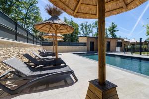 a group of lounge chairs under an umbrella next to a swimming pool at Lodge Spa Celeste in Sarlat-la-Canéda