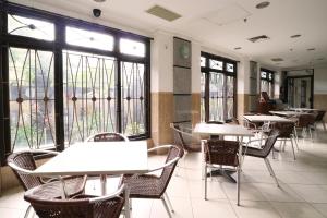 an empty restaurant with tables and chairs and windows at Bali Paradise City Hotel in Denpasar