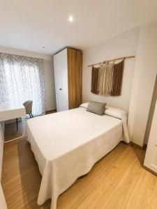 a bedroom with a large white bed and a desk at Tranquilo in Elche