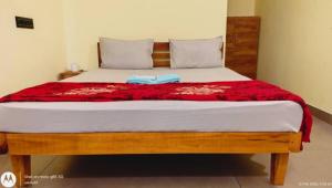 a bed with a red blanket on top of it at The Haira Varkala in Varkala +2 photos