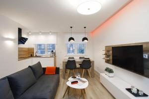 a living room with a black couch and a tv at Apartamenty MISTRAL in Karpacz