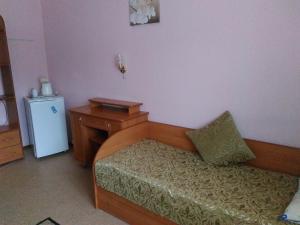 Habitación con cama, escritorio y nevera pequeña. en Hotel Na Kuznechnoy, en Saratov