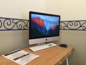 a computer monitor and a keyboard and mouse on a desk at Kyriad Hotel XIII Italie Gobelins in Paris