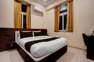 a bedroom with a large bed and two windows at Super Collection O Zero Mile Patna Formerly Chandrashila Residency in Gulzārbāgh