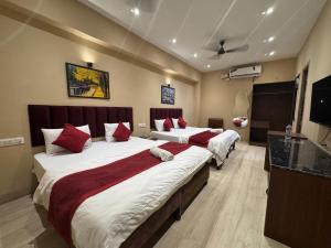 a hotel room with two beds with red pillows at Hotel Green Land in Mathura