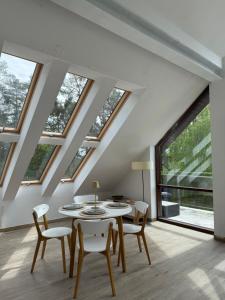 a dining room with a table and chairs and windows at Apartament Art & Lake View in Gryzliny