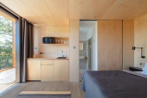 a room with a bed and a kitchen with a window at Kapolcsi Sziklák in Vigántpetend