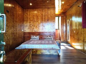 ein Schlafzimmer mit einem Bett in einer Holzwand in der Unterkunft Lal Bangla Homestay in Chaukori