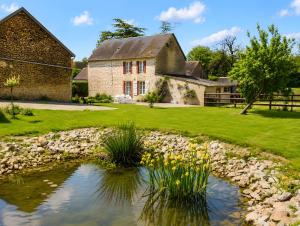 an old stone house with a pond in front of it at La Maison des Filles in Sainte-Scolasse-sur-Sarthe