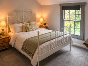 a bedroom with a white bed and a window at Mark's Cottage in North Walsham