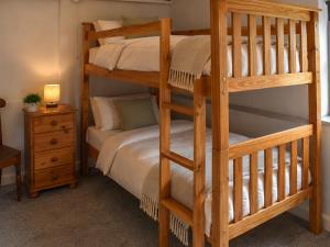 a bedroom with two bunk beds and a bed at Mark's Cottage in North Walsham