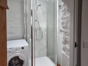 a shower in a bathroom with a washing machine at Mark's Cottage in North Walsham