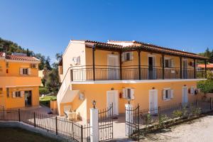 a yellow house with a fence in front of it at Odysseus Apartments in Agios Gordios