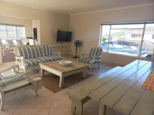 a living room with a table and chairs and a television at Ripples Beach House - 14 sleeper in Port Alfred
