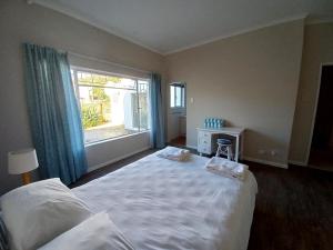 a bedroom with a large white bed and a window at Ripples Beach House - 14 sleeper in Port Alfred