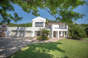 an exterior view of a white house with a yard at Ripples Beach House - 14 sleeper in Port Alfred