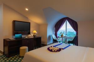 a hotel room with a bed and a desk and a television at Peach Valley Hotel Dalat in Da Lat +50 photos