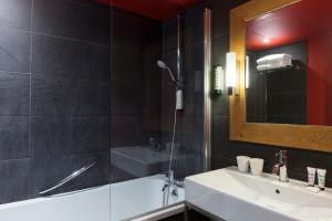 a bathroom with a sink and a tub and a mirror at Hôtel Les Aiglons Chamonix in Chamonix