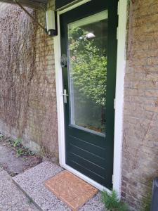 a green door on a house with a window at Onder de regenboog in Egmond aan den Hoef
