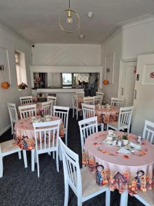 a dining room with white tables and white chairs at Glendor Hotel in Blackpool