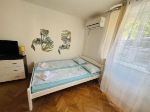 a small bedroom with a bed and a window at Apartmani Luciano in Novalja