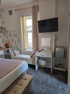 a bedroom with a bed and a desk with a television at Glendor Hotel in Blackpool