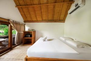 a bedroom with a white bed with a wooden ceiling at Kaia Raya Surf Lodge in Maluk +61 photos