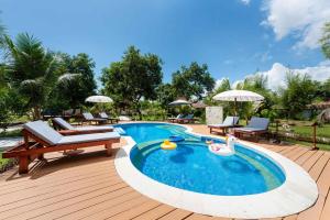 a swimming pool with a deck with chairs and umbrellas at Kaia Raya Surf Lodge in Maluk