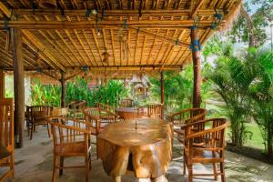 a wooden table and chairs in a restaurant at Kaia Raya Surf Lodge in Maluk