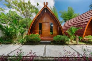 a small wooden house with a red roof at Kaia Raya Surf Lodge in Maluk