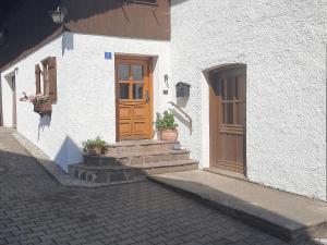 a white building with a wooden door and stairs at Ferienwohnung Mutzenbauer in Bad Endorf