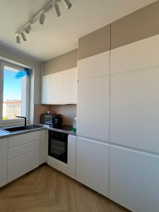 a kitchen with white cabinets and a window at Apartament nad jeziorem Rosnowo in Rosnowo