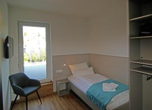 a bedroom with a bed and a chair and a window at Hotel Falken in Hechingen