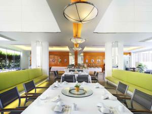 a dining room with white tables and green chairs at Ibis Pattaya in Pattaya +57 photos
