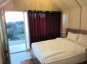 a bedroom with a bed and a large window at Winterfeel Bellmount by Neon Nest in Ooty