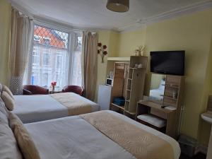 a hotel room with two beds and a television at Glendor Hotel in Blackpool