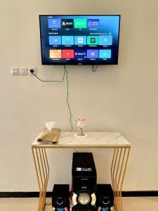 a tv hanging on a wall with a table with a television on it at infinite 88 villa in Batu