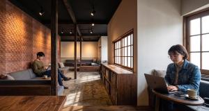 two people sitting in a room with a laptop at Ruhe K in Kusatsu