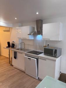 a kitchen with white cabinets and a microwave at Gîte Région des Lacs - SPA et Sauna Privatif in Orgelet