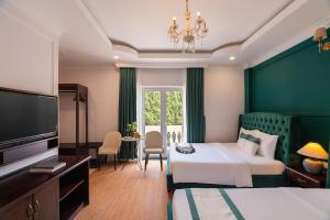a hotel room with two beds and a flat screen tv at Peach Valley Hotel Dalat in Da Lat