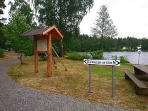 a wooden structure with a sign in a park at EFS-gården in Åsljunga +7 photos
