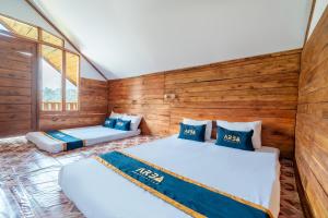 two beds in a room with wooden walls at RB Cottage Resort By ARBA in Palayangan