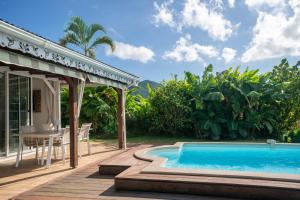 a patio with a pool and a table and a house at Villa Le Nid des Colibris in Gourbeyre