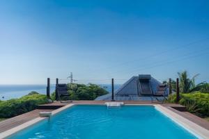 a swimming pool with two chairs and the ocean in the background at Villa Le Nid des Colibris in Gourbeyre